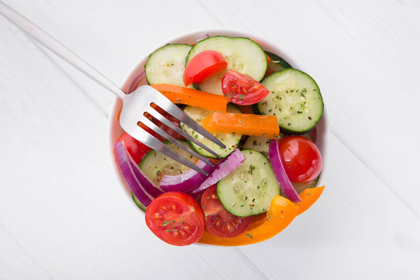 Čerstvý zeleninový salát v misce na stole z bílého dřeva. Zdravá strava. Horní pohled - Fotografie, Obrázek