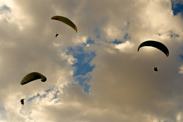 three paragliding flying in a cloudy sky - Фото, изображение