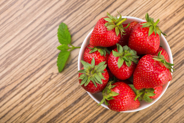 Fresh red strawberry in a bowl on table. Sweet summer dessert background. top view - Photo, image