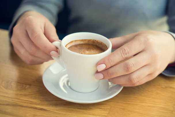Mulher loira com xícara de café branco se senta em um café perto da janela. Almoço fundo pausa
 - Foto, Imagem