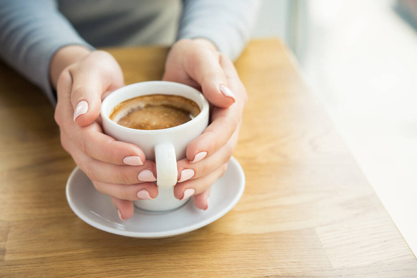 Mulher loira com xícara de café branco se senta em um café perto da janela. Almoço fundo pausa
 - Foto, Imagem