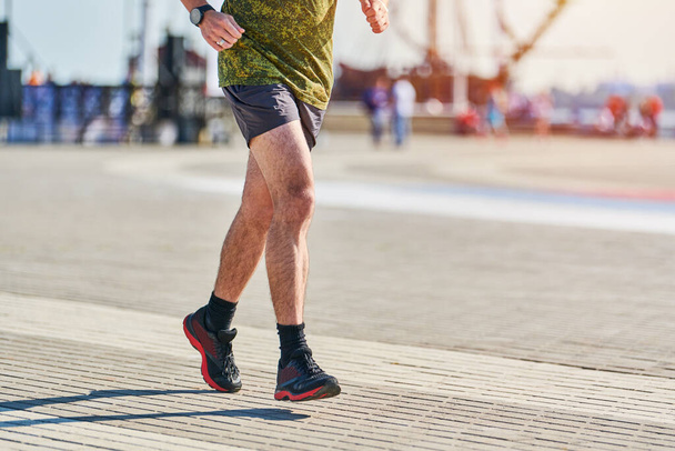 Běžící muž. Atletický muž běhá ve sportovním oblečení na městské silnici. Zdravý životní styl, sportovní koníček. Pouliční cvičení, sprintování venku - Fotografie, Obrázek