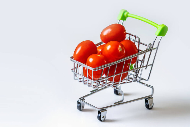 Tomatoes in a grocery cart. A shopping basket filled with fresh vegetables is isolated. The concept of healthy eating. - Fotografie, Obrázek