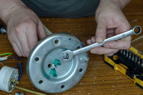 Water heater repair part 5 7. Hands of a man with a wrench will assemble the boiler parts. Locksmith middle-aged European race. Service and repair of household appliances. - Photo, Image