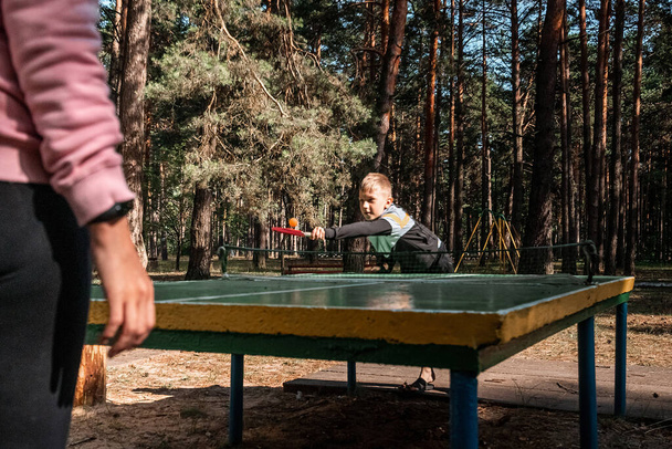 A boy plays ping pong with his mom, sports games. The concept of family ties, intergenerational communication, parents and children - Fotoğraf, Görsel