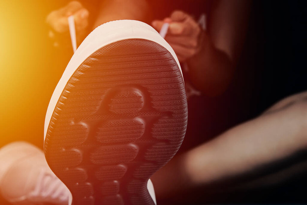 Nainen sitoo kengännauhat tummalla pohjalla oleviin lenkkareihin. Fitness urheilija valmis liikuntaan - Valokuva, kuva
