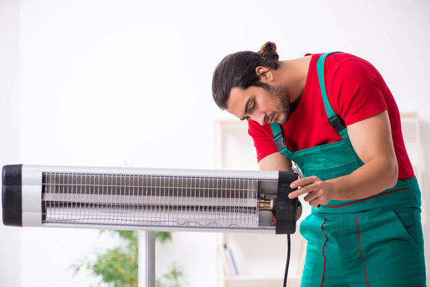 Young male contractor repairing heater indoors - Foto, afbeelding