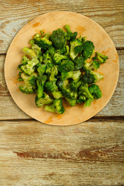 Scattered frozen broccoli on a round wooden board. - Valokuva, kuva