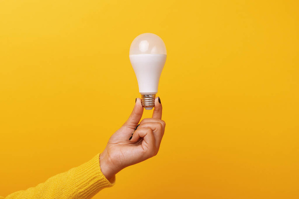 лампочка в руке на желтом фоне - Фото, изображение