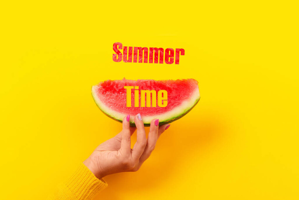 watermelon slice in hand over yellow background, summertime concept - Фото, изображение