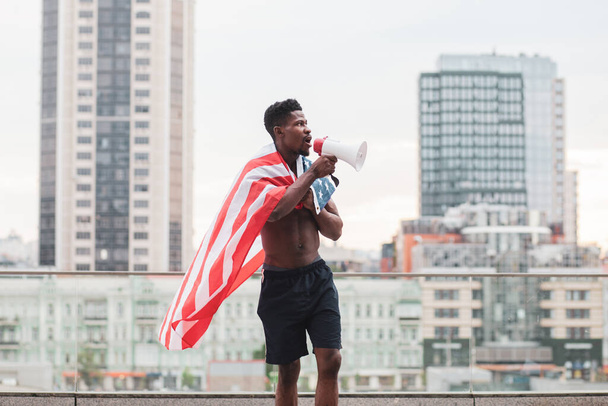 zwart leven materie concept. Agressieve Afro-Amerikaanse man met Amerikaanse vlag protesten en geschreeuw, patriot activist van Amerika maakt rebellie, kopieer ruimte - Foto, afbeelding