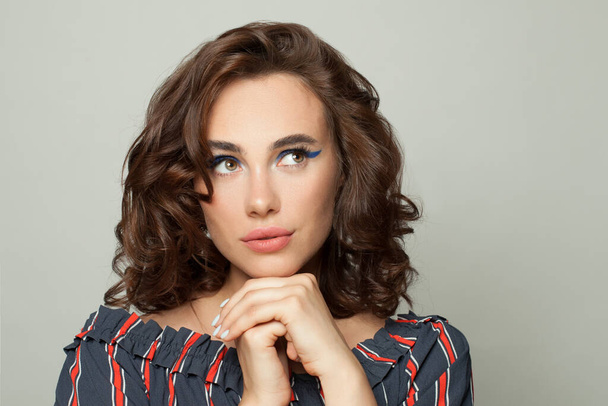 Attractive woman with brown curly bob hairdo looking up aside on white - Photo, Image