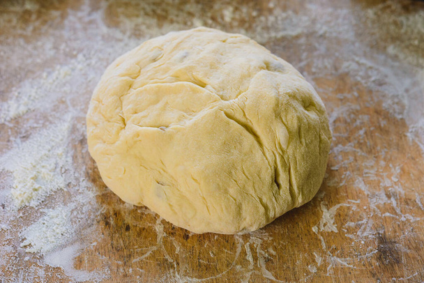 A képen egy nő kenyeret formál. Kenyér mazsolával, édes. Ez a kenyér húsvétra készült.2020 - Fotó, kép