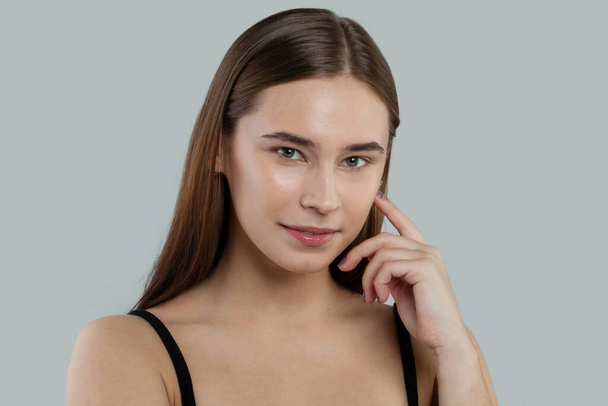 Cute young woman with clear skin and straight hair. Skincare and facial treatment concept - Photo, Image
