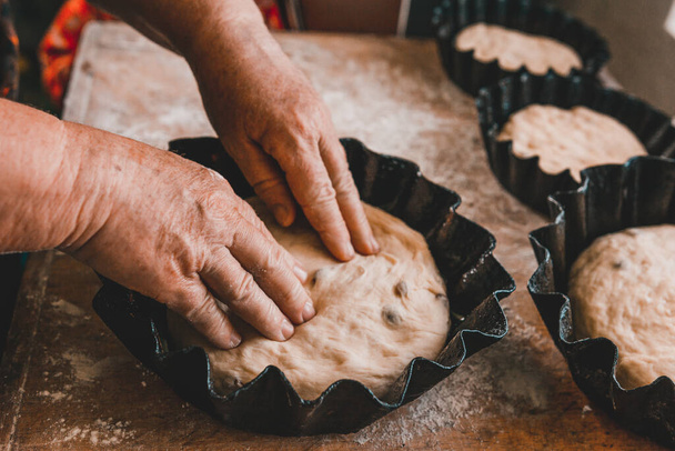 Frau knetet und formt frisches Brot zu Formen. Brot mit Rosinen, süß, zum Backen mit Hühnerdotter bestrichen. 2020 - Foto, Bild