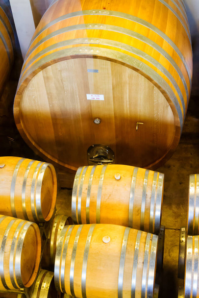 Barricas de vino apiladas en la bodega de la bodega
. - Foto, Imagen