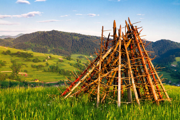 Традиционные словенские конструкции для сушки сена и хранения древесины, сено на холмистом поле в горах Бескид Садецкий, Польша
 - Фото, изображение