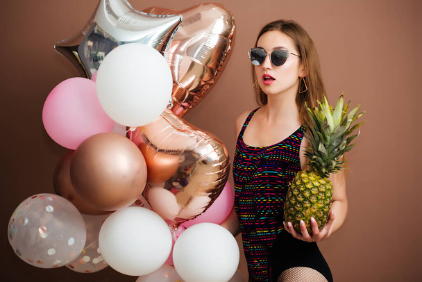 erotic swimsuit girl with pineapple fruit holding balloons - Foto, imagen
