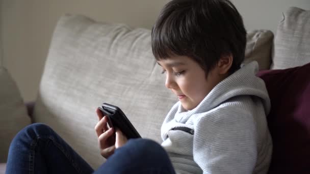 Kind selbstisoliert mit Handy für seine Hausaufgaben, Kind mit Handy im Gespräch mit seinem Freund im Internet, covid lock down, Schulbildung zu Hause, Social Distance, E-Learning Online-Bildung - Filmmaterial, Video