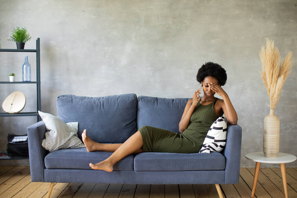 Unhappy African American woman talking on the phone, angry girl talking on the phone, discharged or broken mobile device, problem with phone, sitting on sofa - Foto, Bild