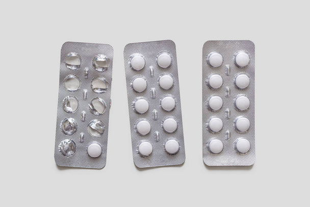 Наборы волдырей с белыми таблетками с пленкой, предписанными врачом на светлом фоне
 - Фото, изображение