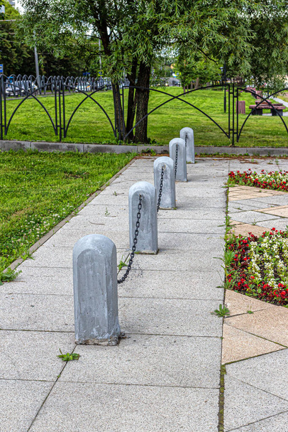 Zäune in Form von Steinsäulen, die durch eine gusseiserne Kette auf dem Stadtplatz verbunden sind - Foto, Bild