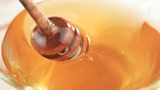 Un bastoncino di miele di legno ruota lentamente nel terreno del miele. - Filmati, video