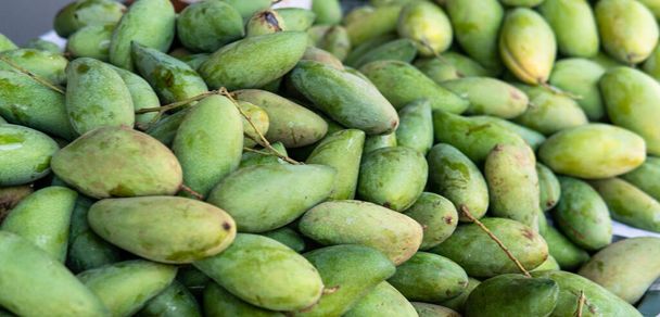 πράσινα μάνγκο ξαπλωμένα στον πάγκο της αγοράς. Εξωτικά φρούτα της Ασίας - Φωτογραφία, εικόνα