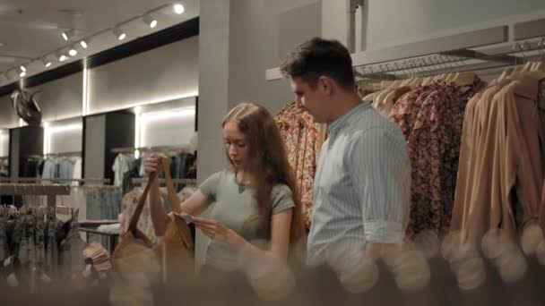 Uomo e donna a piedi indoor di moda negozio di vestiti - Filmati, video