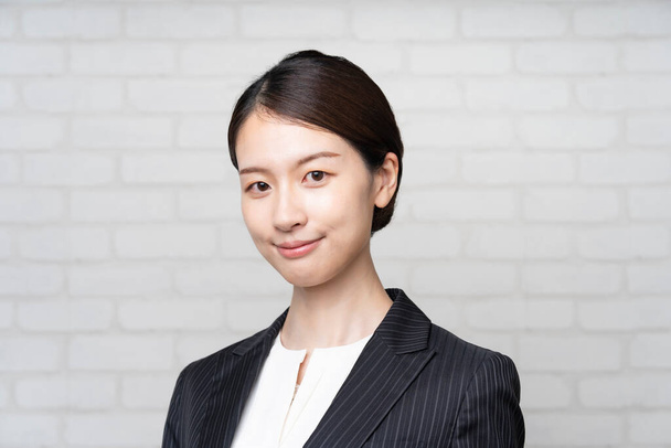 Portret van een lachende Aziatische jonge zakenvrouw in een pak - Foto, afbeelding