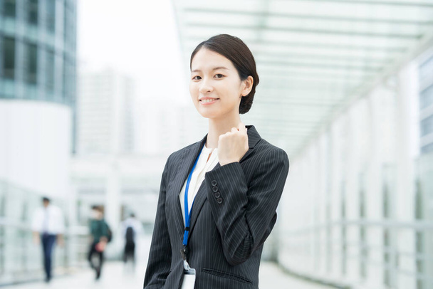 Азиатская молодая деловая женщина в костюме позирует с улыбкой и аплодисментами
 - Фото, изображение