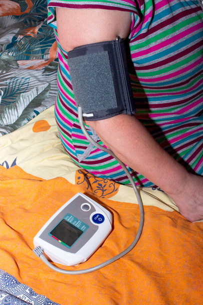 Una mujer mide la presión usando un dispositivo de medición de presión
. - Foto, imagen