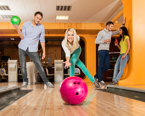 Group of four young smiling people playing bowling - Foto, Imagem