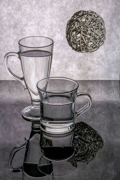 zátiší se skleněnými poháry s tekutinou na šedém pozadí - Fotografie, Obrázek