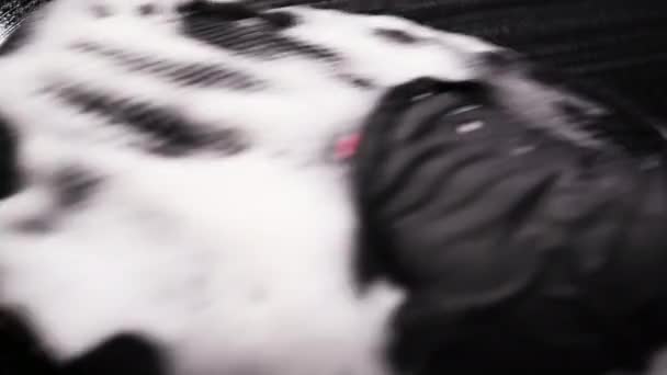 Nagranie makro człowieka czyści powierzchnię samochodu z kropli za pomocą wycieraczki. Pęknięcie pęcherzyków po wytarciu. - Materiał filmowy, wideo