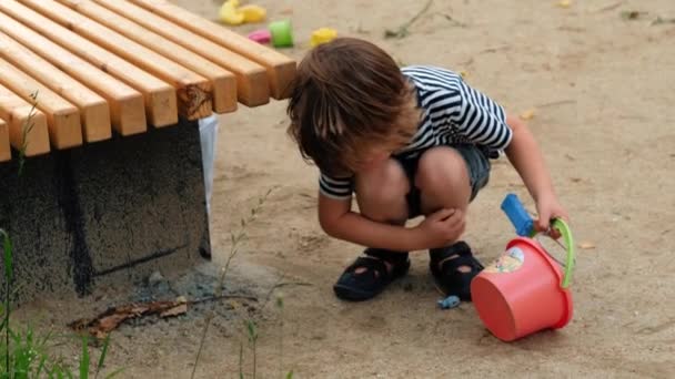 Μικρό παιδί παίζει με πλαστικά παιχνίδια στο δρόμο - Πλάνα, βίντεο