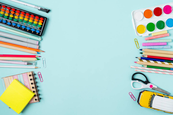 Flat lay of modern bright blue office desktop with school supplies on table around empty space for text. Top view Back to school concept. - Photo, Image
