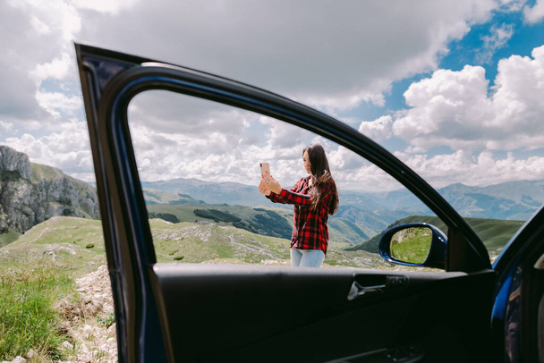 beautiful woman tourist using smartphone in mountains and travel by car - Photo, Image