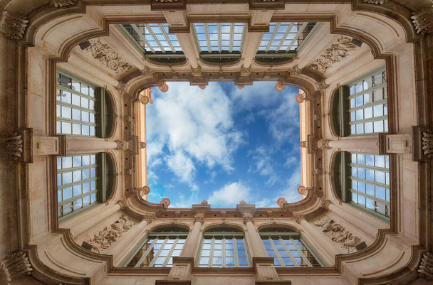 Dolní široký úhel pohledu na historické vnitřní nádvoří s krásným komplexem fasádních budov s modrou oblohou a mraky a odraz v oknech v Barceloně, Španělsko. Geometrický tvar - Fotografie, Obrázek