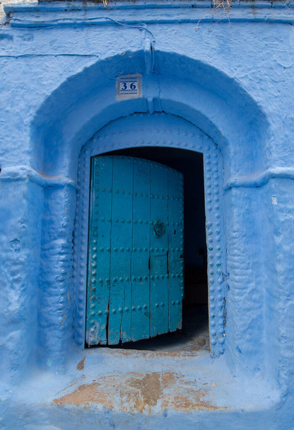 Típico, viejo, azul intrincadamente tallado, tachonado, puerta riad marroquí y marco de puerta y casa antigua en CHEFCHAOUEN, MARRUECOS. Hermosa vista de la ciudad azul en la medina. casas pintadas - Foto, imagen