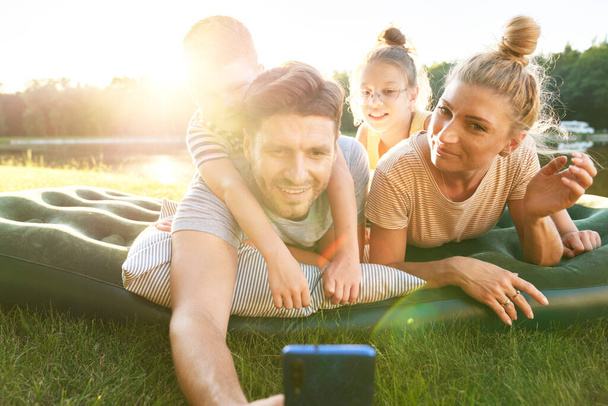                                Família tirando uma selfie durante as férias junto ao lago
 - Foto, Imagem