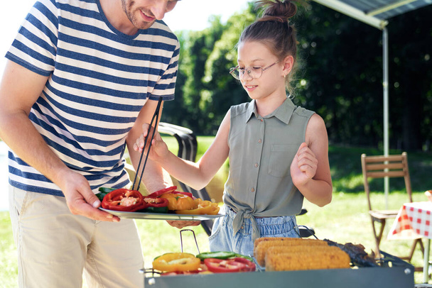                                Isä ja tytär tarjoilevat vihanneksia grillillä - Valokuva, kuva