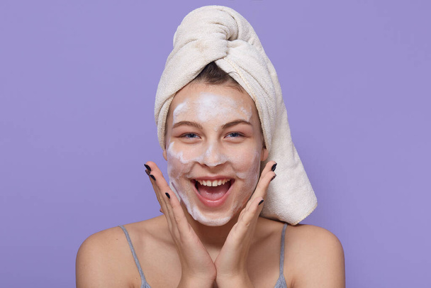 Girl wearing hydro gel mask, using facial mask for skin treatment, looks happy and excited, keeping palms near cheeks, yelling something happily, enjoying spa procedures. - Fotografie, Obrázek