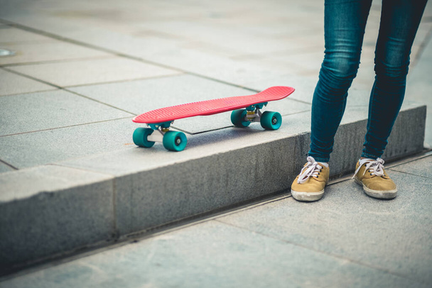 Asian woman with skatebaord in modern city - Фото, зображення