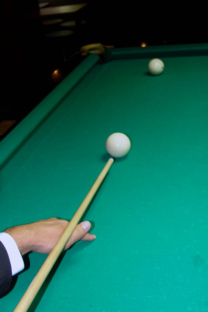 male hand with a billiard cue, two billiard balls on a pool table, view from the top - Фото, изображение