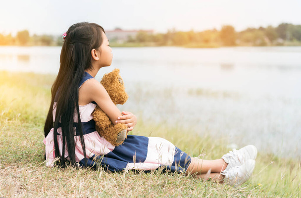 Happy Child hug teddy bear in green park playground. Teddy bear best friend for little kids cute girl. Autism happy funny playing together on playground in happiness family feel love and warm hugs - Photo, Image