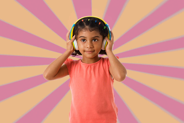 Music, childhood and technology concept.Child with headphones over geometric background - Photo, Image