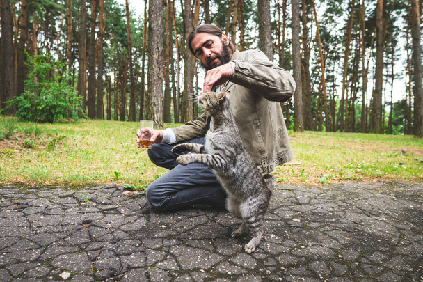 A man plays with a gray tabby cat. The cat performs the trick. - Foto, Imagen