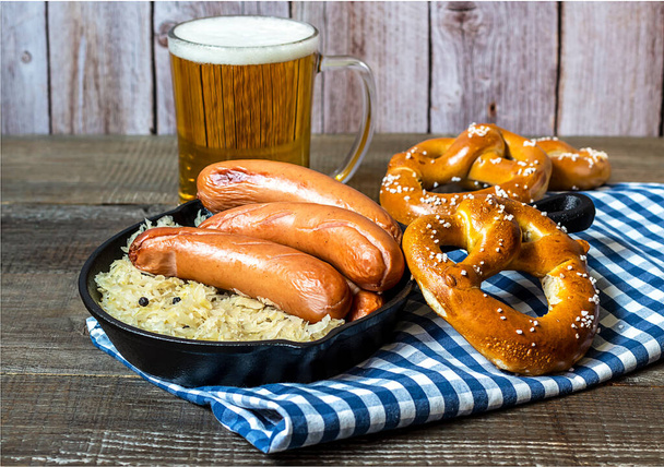 Il concetto dell'Oktoberfest. Salsicce tradizionali tedesche bratwurst con crauti, birra e pretzel sul tavolo di legno.  - Foto, immagini