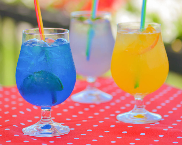 Three ice soft drinks with soda water, refreshing summer beverage. Alcohol cocktail with ice in a glass outside. Copy space banner. - Foto, imagen